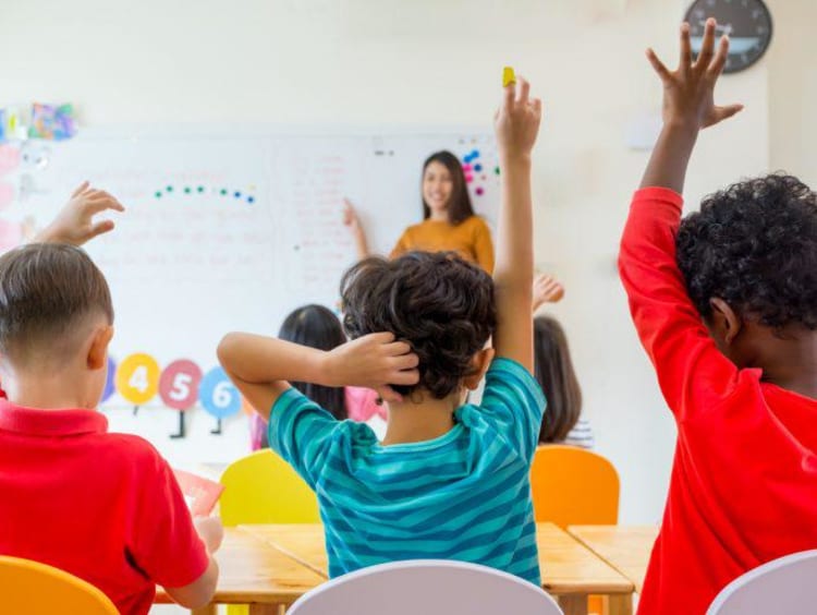 Elementary students raising their hands