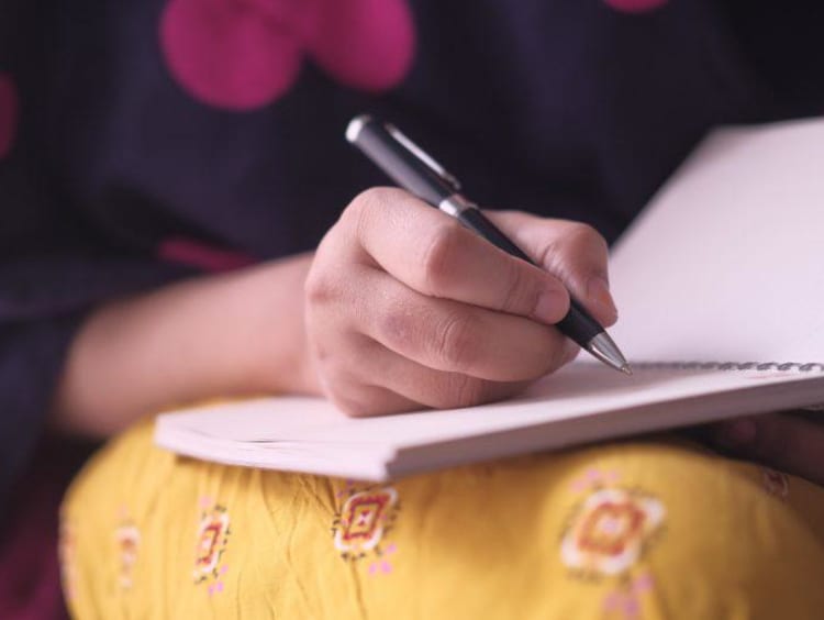 A student taking notes on a paper pad