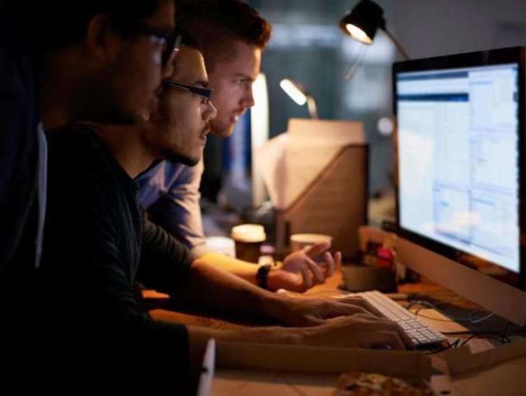 three guys in front of a computer