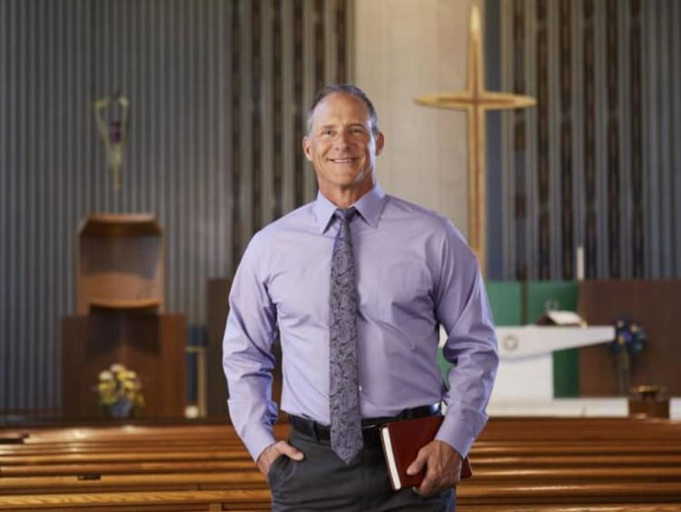 A man in a purple shirt standing in a church