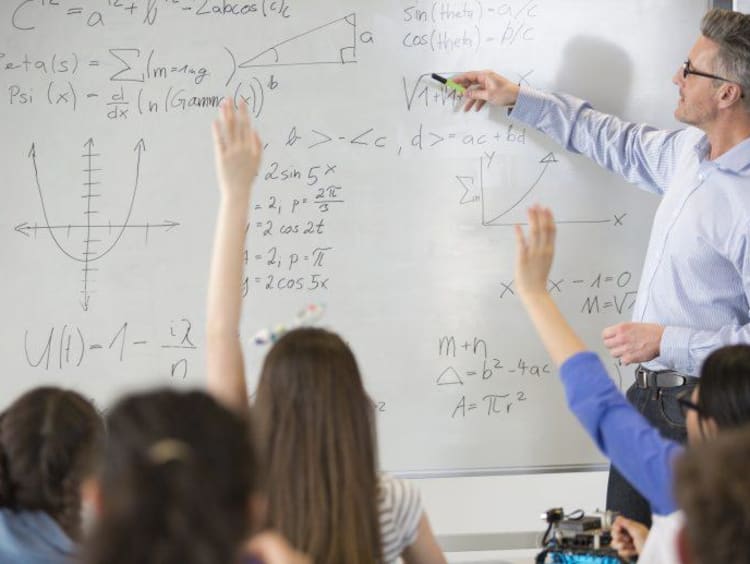 Male teacher leading physics lesson at whiteboard in classroom