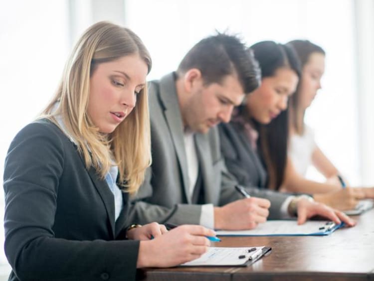 four people sitting at a table signing paperwork