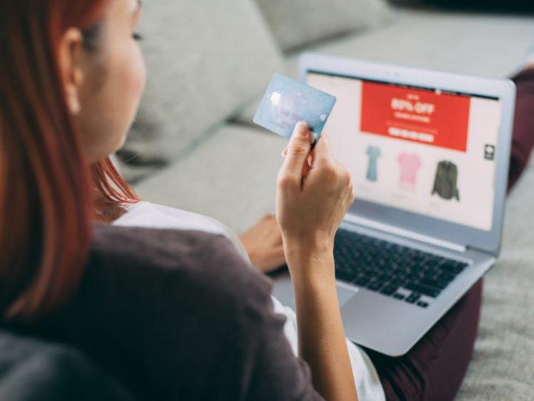 Woman shopping online with card in hand