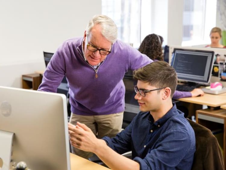 Programmer working at a computer with his professor