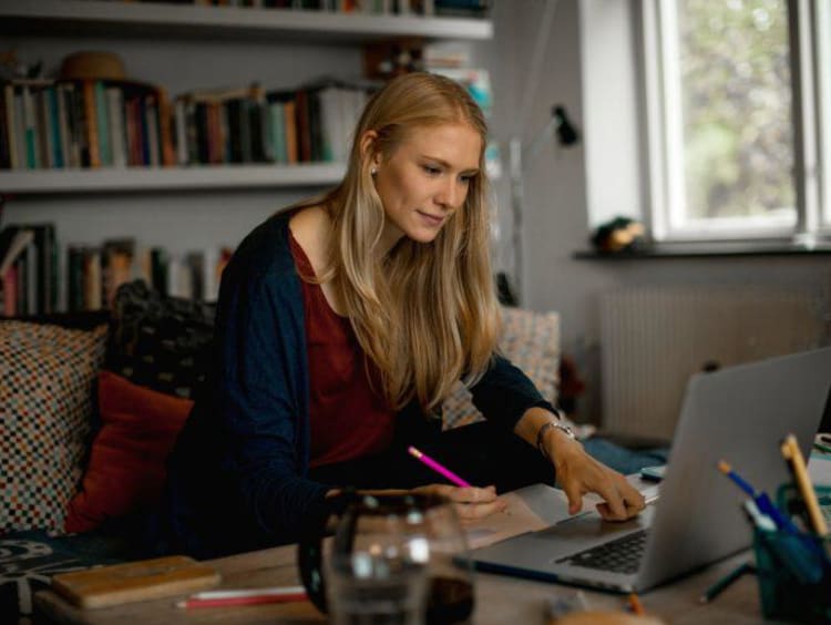 Blonde female student takes notes from online counseling class