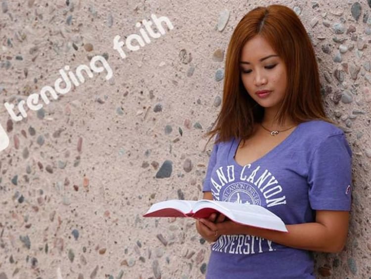 Female student in purple v-neck GCU shirt reads the Bible