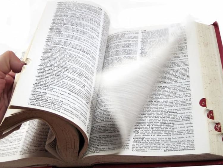 Person thumbs through a big dictionary book