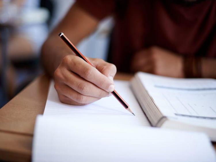 Student taking notes from a textbook