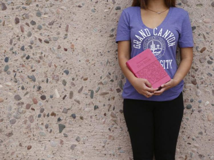 A student in a GCU shirt holding the Bible