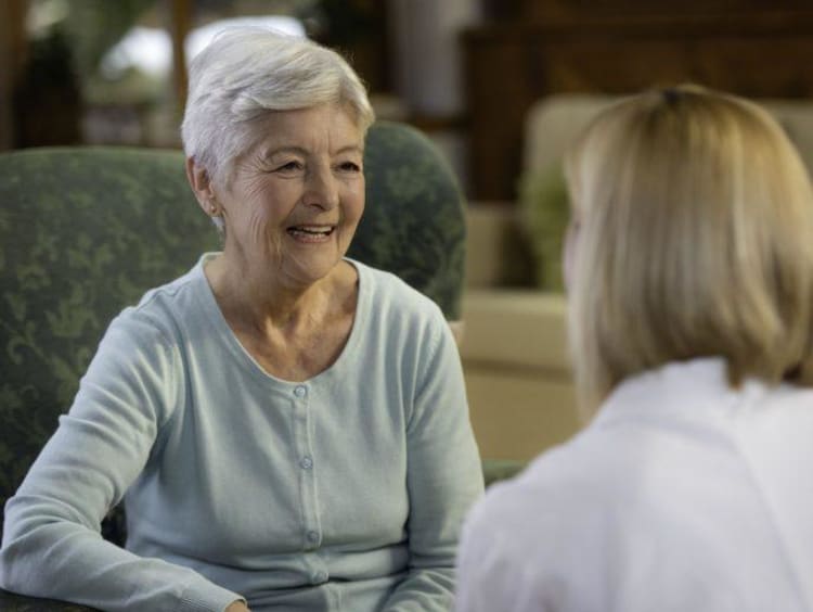 Older woman with short white hair smiles at a doctor in front of her