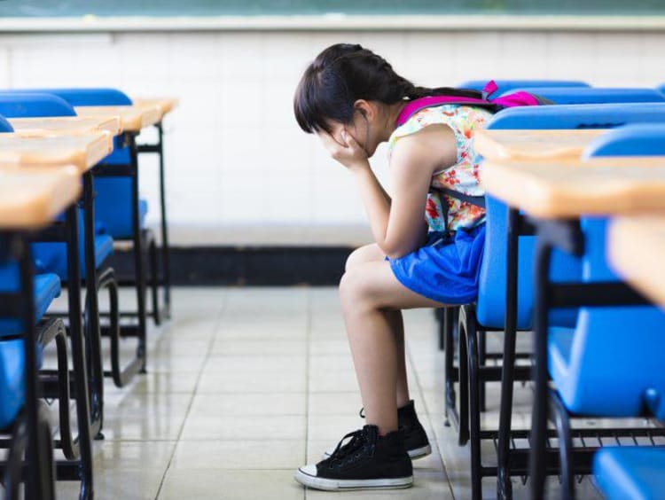 kid sitting in a classroom with head in hands