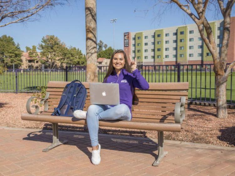 Tatum sitting on a bench on campus