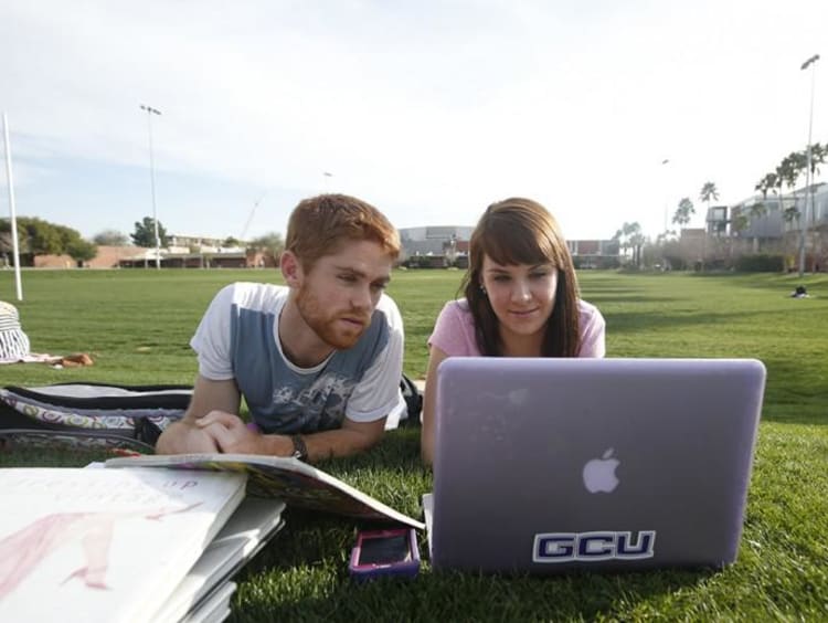 two students looking at a laptop