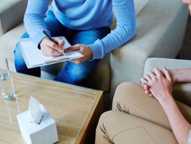 Tissues on table while a counselor takes notes during a session