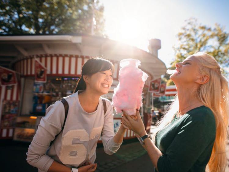 two girls at a carnival eating cotton candy