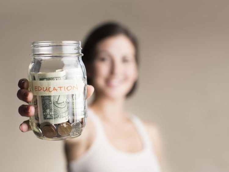 Woman holds out a jar labeled Education with money in it 