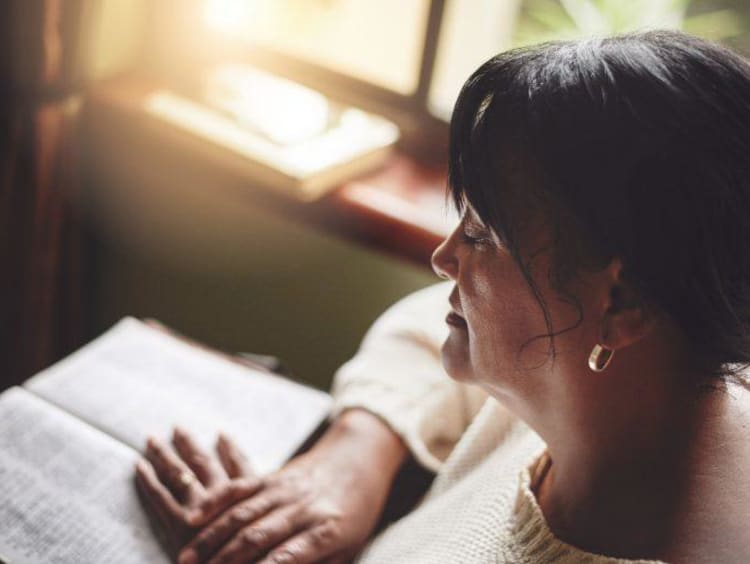 a woman praying over her Bible