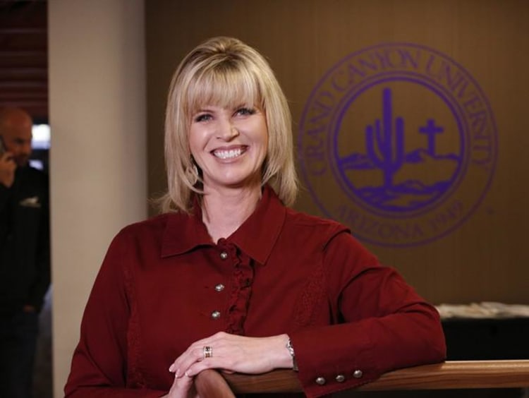 Older blonde woman smiles brightly inside GCU's College of Doctoral Studies