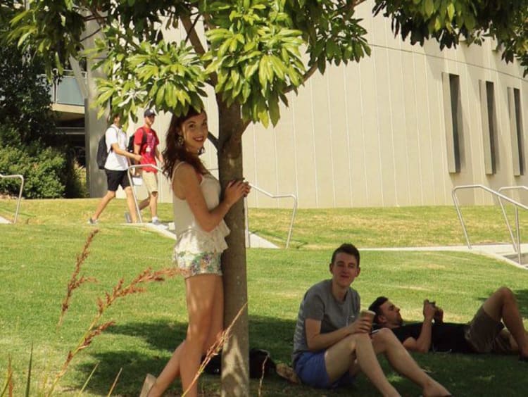Kaitlyn poses by a tree with another international student