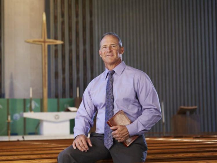 Man in a purple shirt holding a Bible