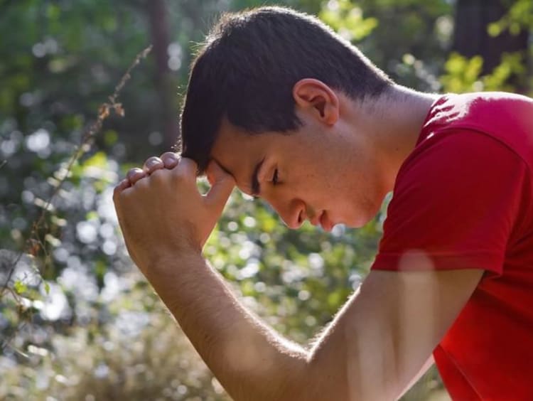 A man hanging his head in the wilderness