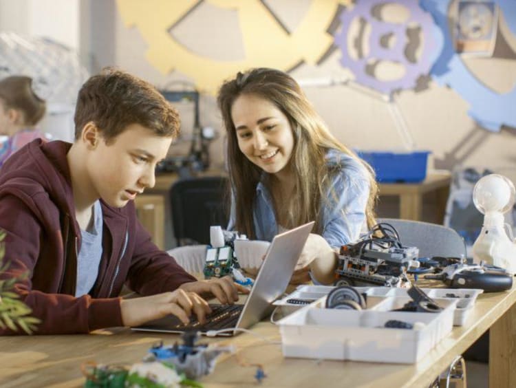 Students look excited on laptop with robotic equipment on table