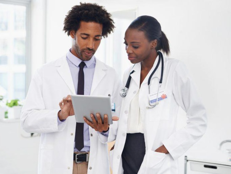 Two African-American doctors review results on tablet