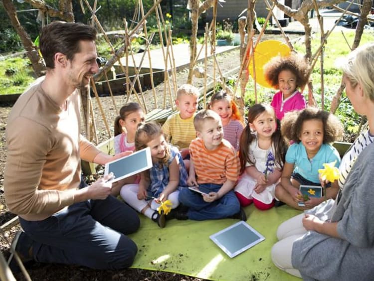 two adults sitting with group of kids