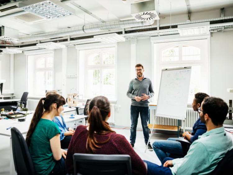 University Tutor Speaking To Students During Seminar