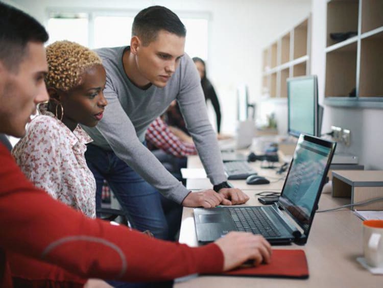 three people focusing on a computer