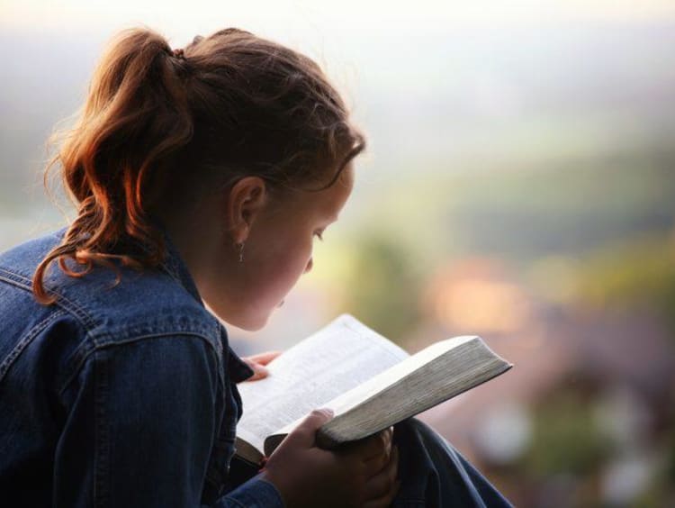 woman reading her bible outside