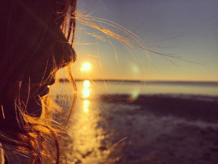 Woman standing in front of an ocean sunset