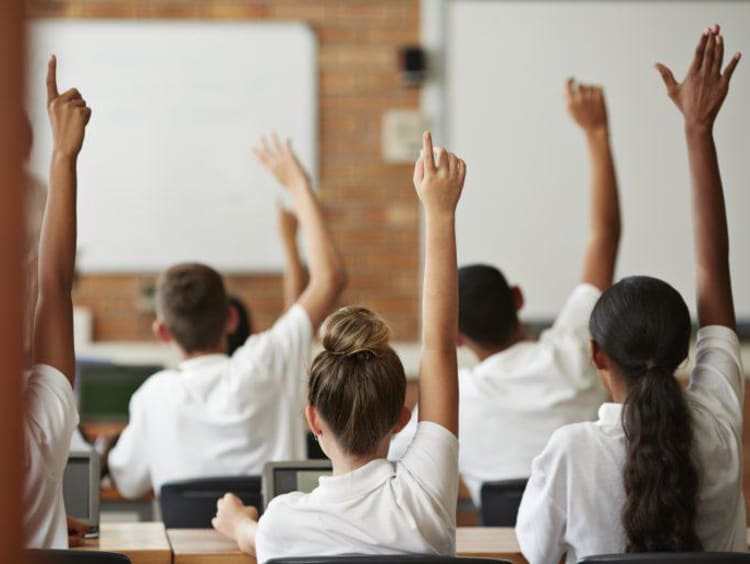 students in uniforms raising hands