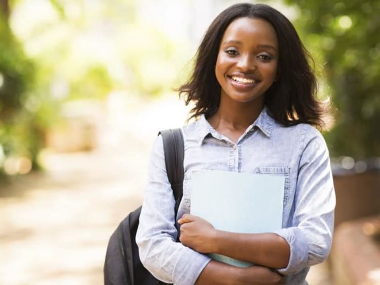 girl wearing backpack and holding notebook