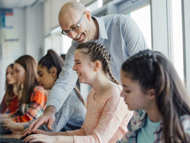 Adult man helping group of girls at school