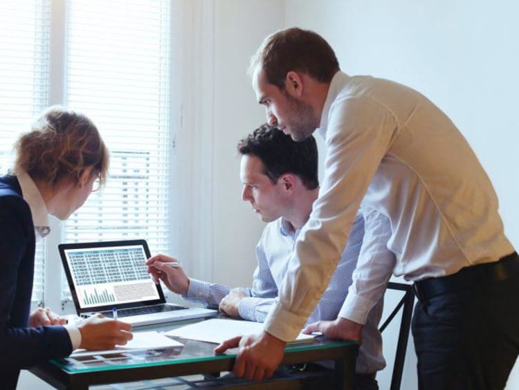 Business analyst shows two other professionals a report