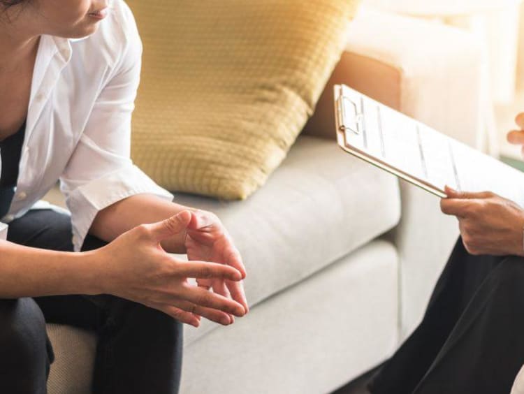 Counselor sitting beside client with clipboard