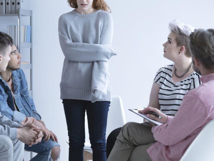 Girl holding her arm in a group counseling setting 