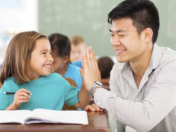 Male teacher gives younger female student a high five