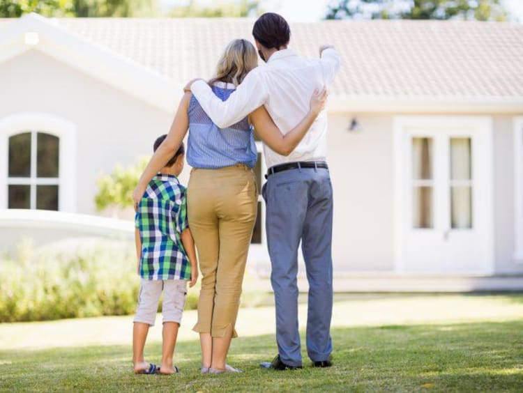 family hugging and looking at a house