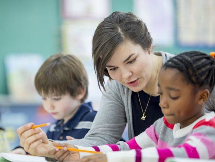 Teacher helps a young student with writing assignment