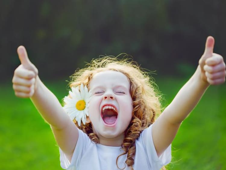 Girl in a field holding two thumbs up