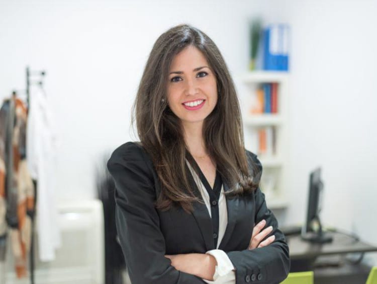 Young professional counselor stands in her office with arms crossed while smiling