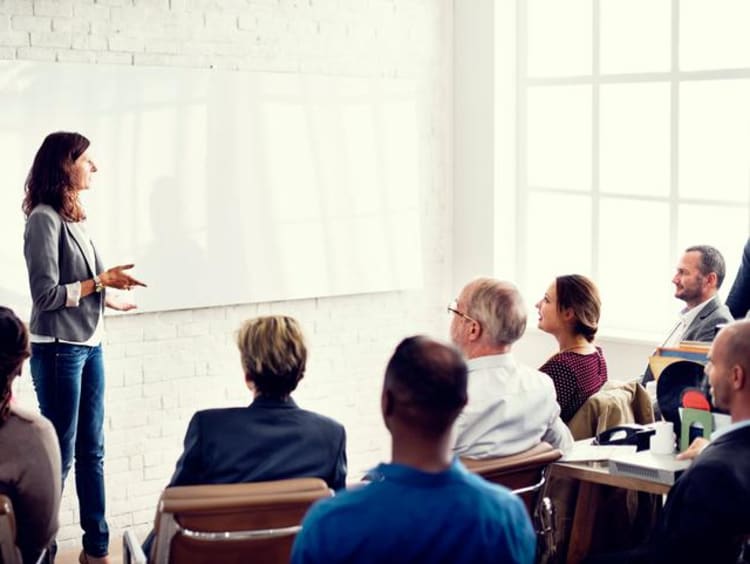 Woman stands in front of group of adult learners