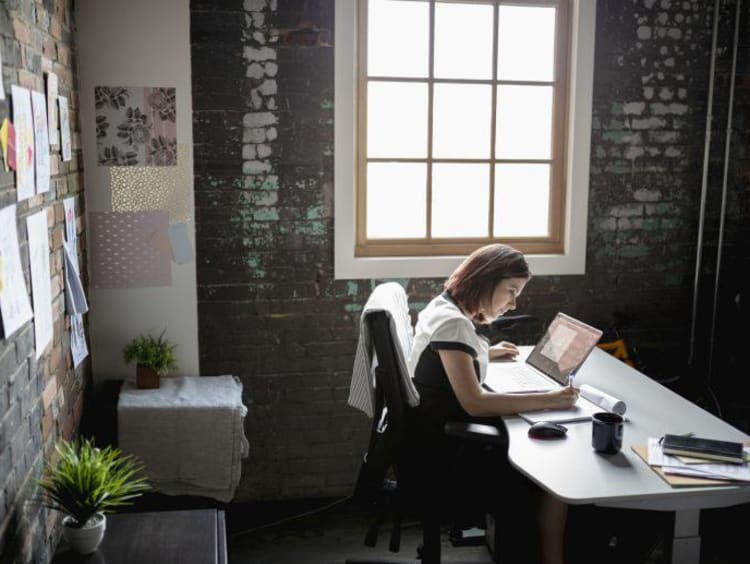 Woman sitting at desk in office next to window