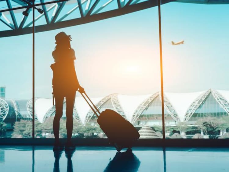 Female student watching a plane take off in an airplane terminal