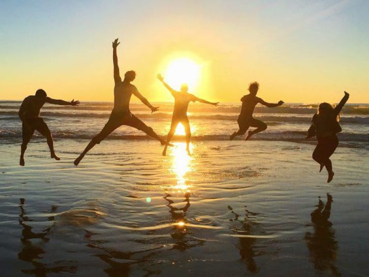 Students holding hands on a trip and posing for a picture