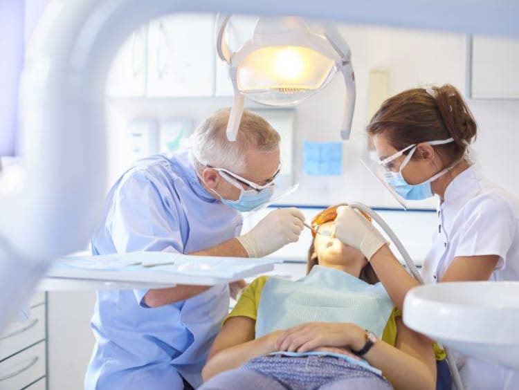 Dentist and hygienist work on a patient's teeth