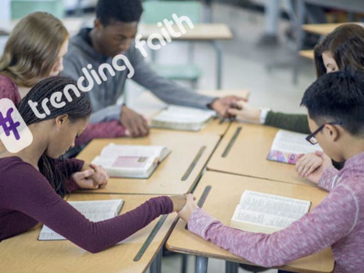 A group of students praying in a circle under the Trending Faith logo