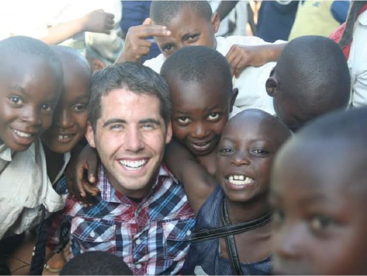 A man surrounded by a group of happy children